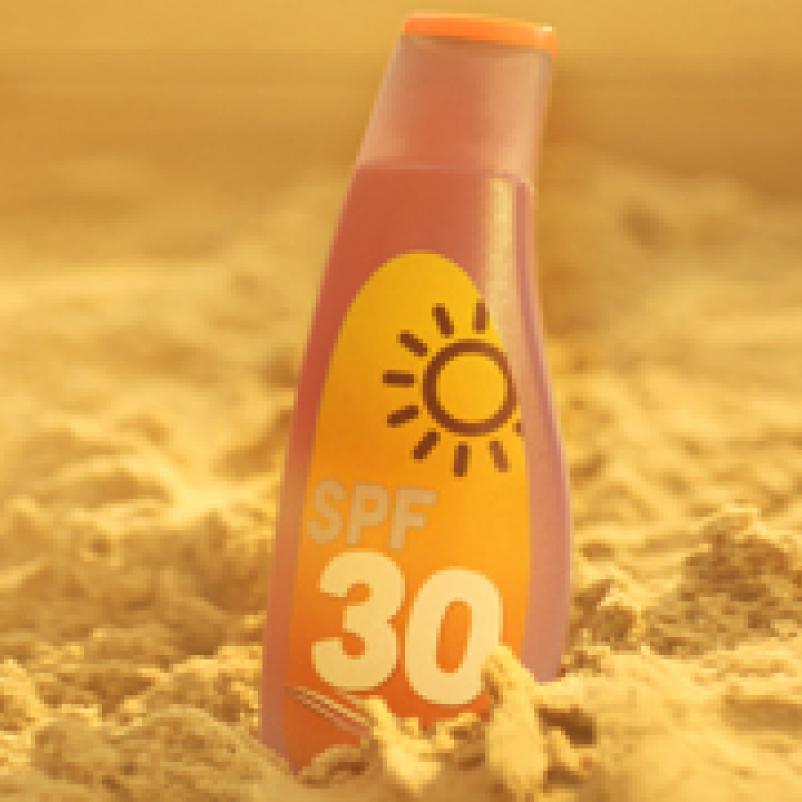 Fles zonnebrandcreme in het zand