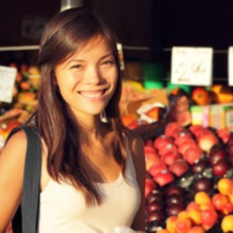 Jonge vrouw voor marktkraam met fruit