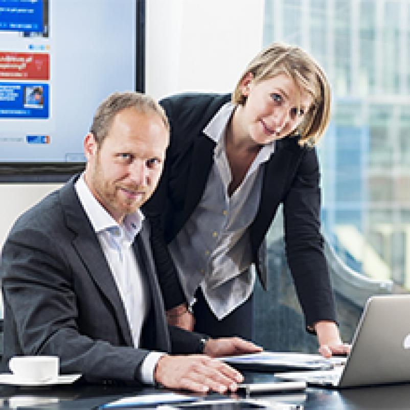 Twee collega's (man en vrouw) aan bureau voor laptop