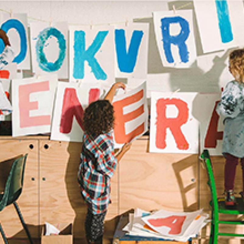Kinderen hangen vellen met letters op aan muur die Rookvrije Generatie vormen