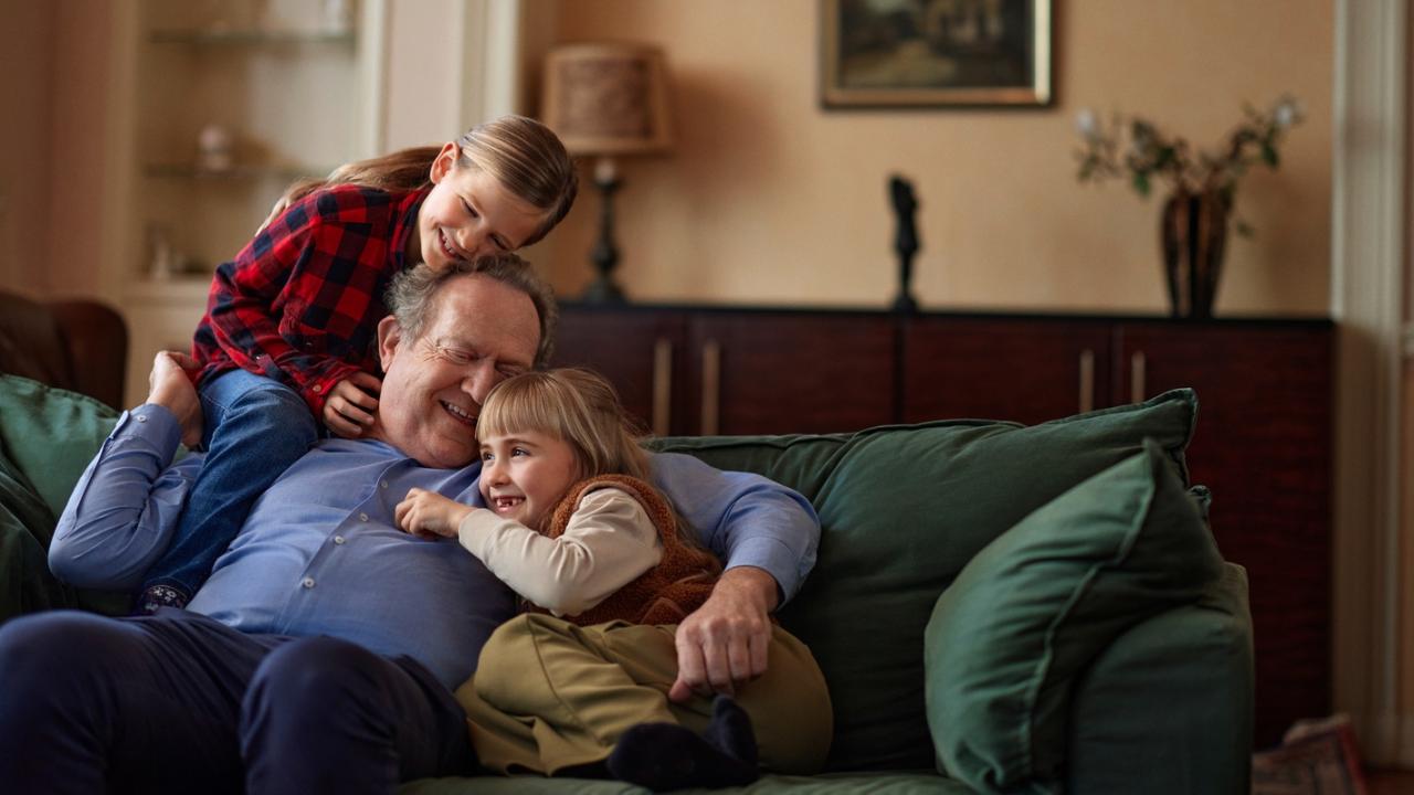 Opa met kleindochters lachend op de bank